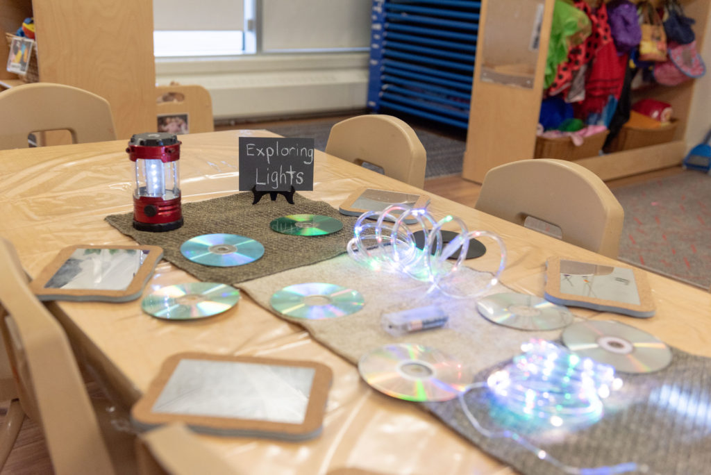 A variety of mirrors and other reflective objects laid out on a table at the Summerside location to encourage toddlers to explore light.